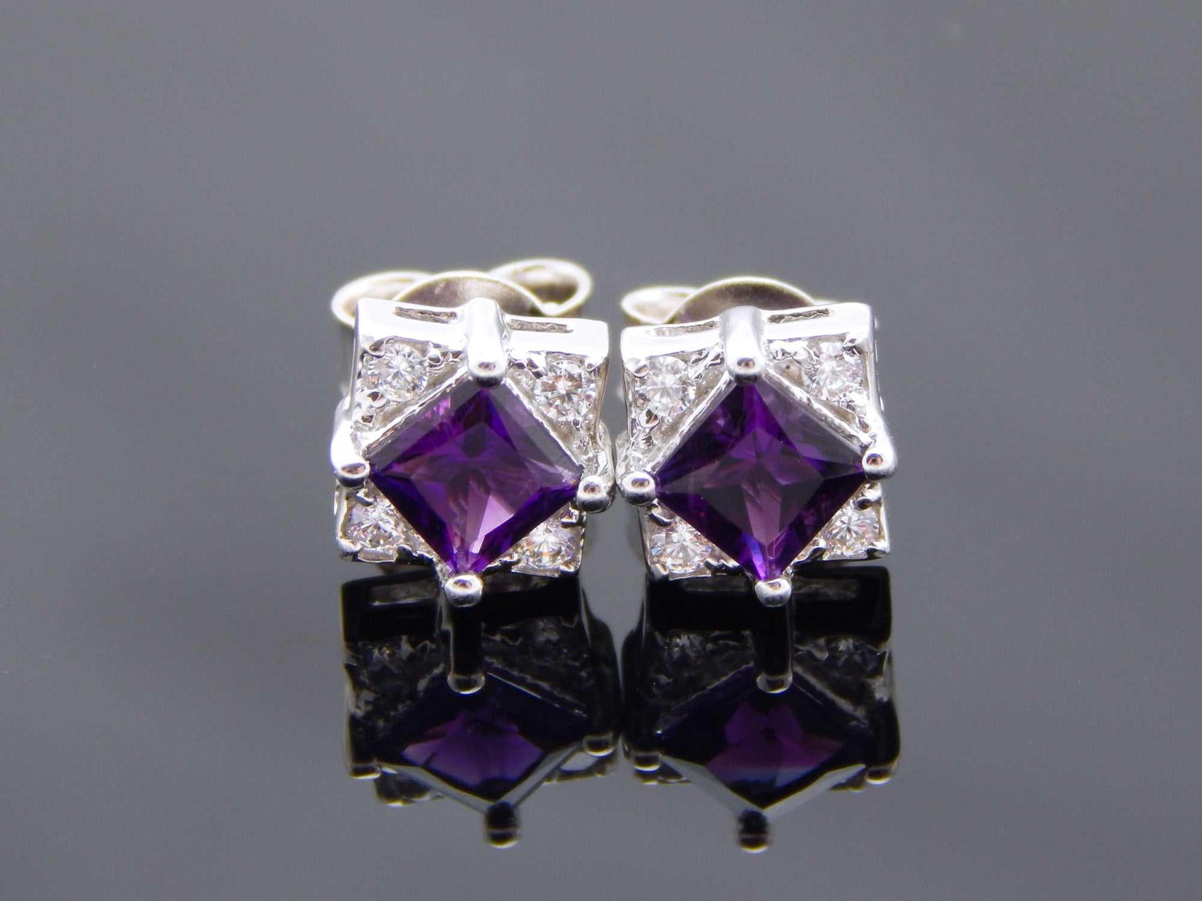 Cushion cut purple amethyst stud earrings in 925 sterling silver with cubic zirconia accents.